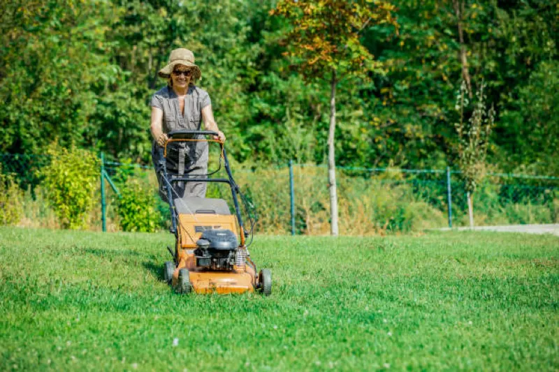 lady cutting grass wearing hat and sunglasses